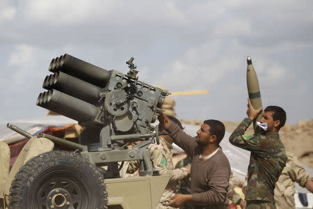 Iraqi security forces and Shi'ite fighters reload a weapon during clashes with Islamic State militants in Salahuddin province March 2, 2015. REUTERS/Thaier Al-Sudani