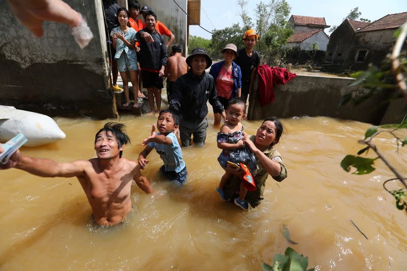 Residents get money from a volunteer at a flooded area in Quang Binh province