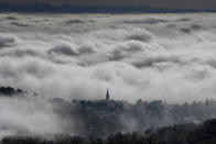 The village of Saint Cyr au Mont d'Or, around Lyon, central France, is seen through the clouds, Friday, Nov. 15, 2019. A dump of heavy snow in southern France has brought down power lines and trees, killing one person, and caused widespread traffic disruption. (AP Photo/Laurent Cipriani)