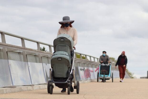 People push strollers on the Flora Footbridge across the Rideau Canal in Ottawa on May 6, 2021, during the COVID-19 pandemic. When will things go back to normal? CBC Ottawa asked some experts some questions that may be on your mind. (Trevor Pritchard/CBC - image credit)