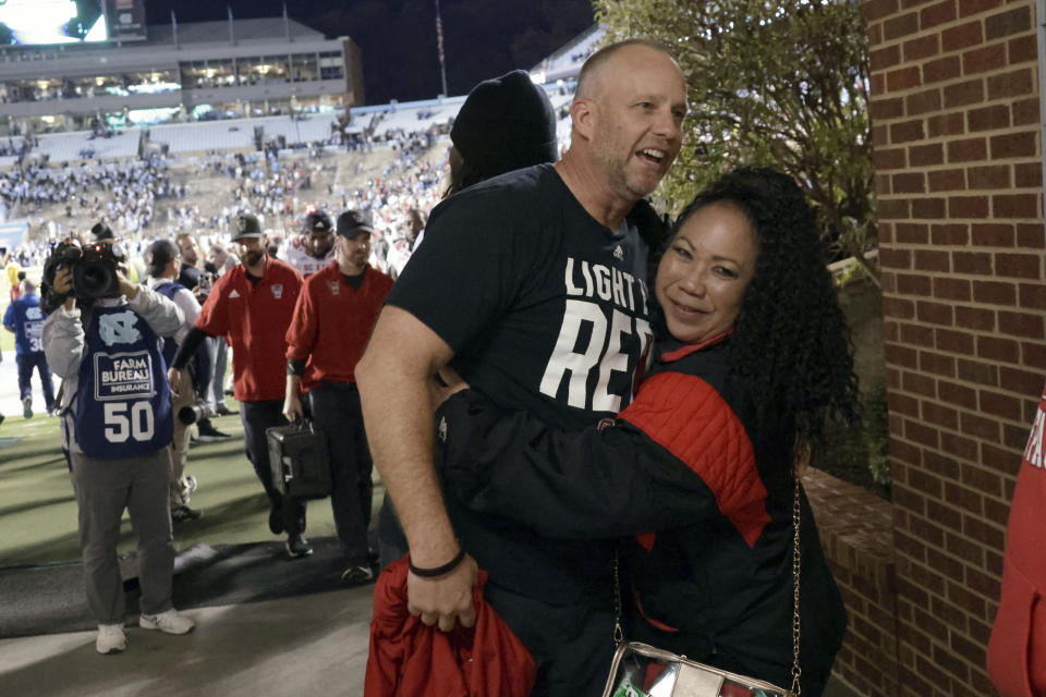 North Carolina State head coach Dave Doeren, left, celebrates with a fan after his team defeated North Carolina in overtime in an NCAA college football game Friday, Nov. 25, 2022, in Chapel Hill, N.C. (AP Photo/Chris Seward)