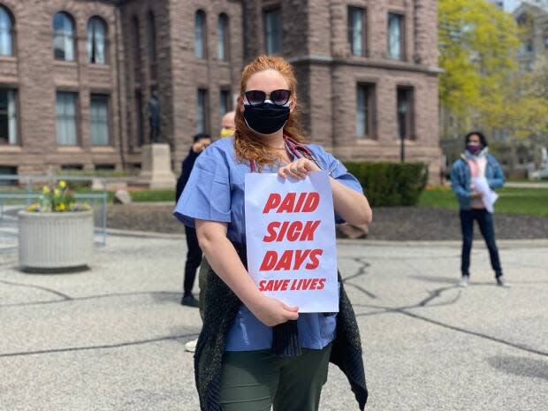 Leah Bennett, a University of Toronto medical student, holds a sign at Queen's Park. Health care workers staged a masked and physically distanced demonstration on Sunday to call on the province to stop playing politics with its pandemic response. (Talia Ricci/CBC - image credit)