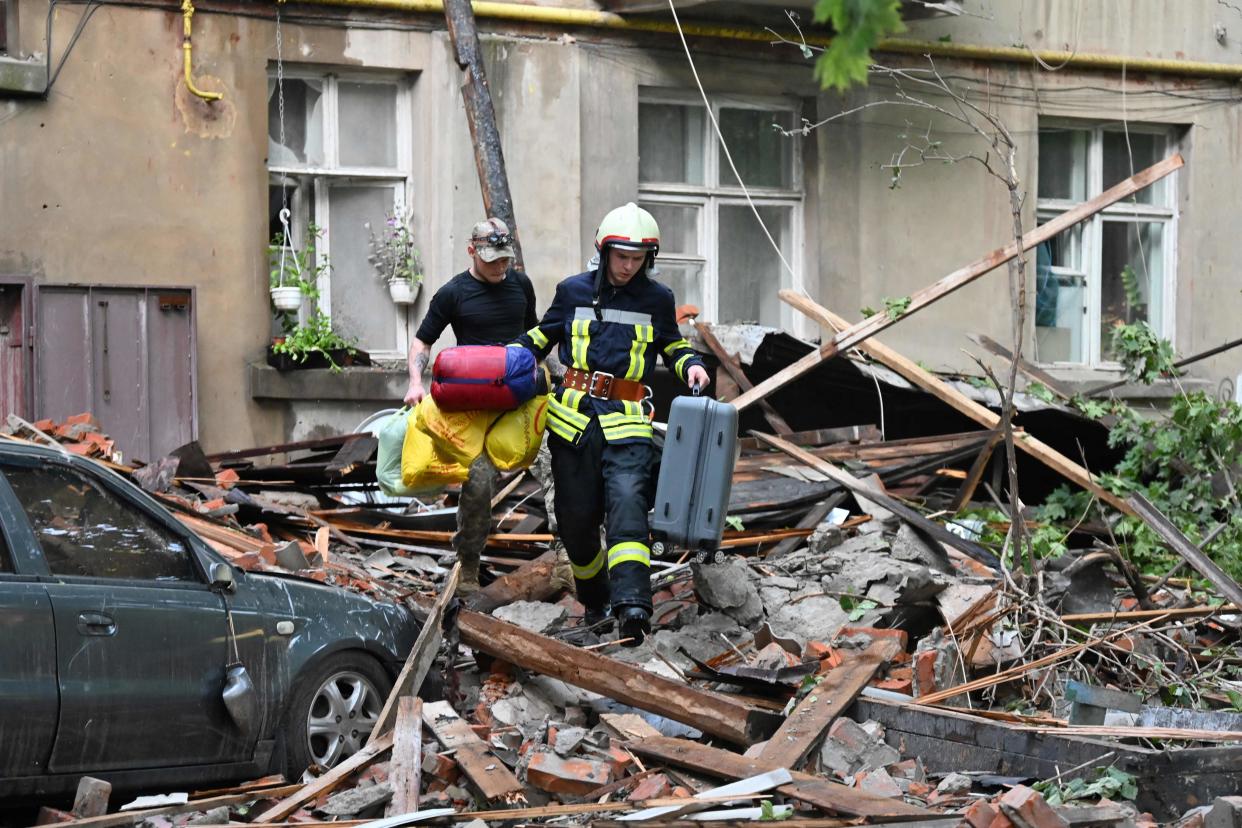 A rescuer helps a local resident to carry his belongings out from a five-storey residential building partially destroyed after drones attacks killed two and wounded 19 (AFP via Getty Images)
