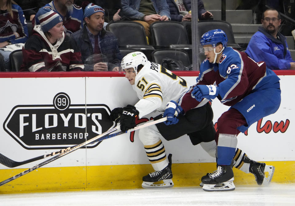 Boston Bruins center Matthew Poitras, left, drives along the boards past Colorado Avalanche defenseman Caleb Jones, right, in the second period of an NHL hockey game Monday, Jan. 8, 2024, in Denver. (AP Photo/David Zalubowski)