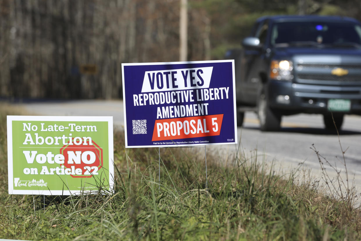 A truck drives by campaign signs opposing and supporting a proposed amendment to the Vermont Constitution that would guarantee access to reproductive rights, including abortion.