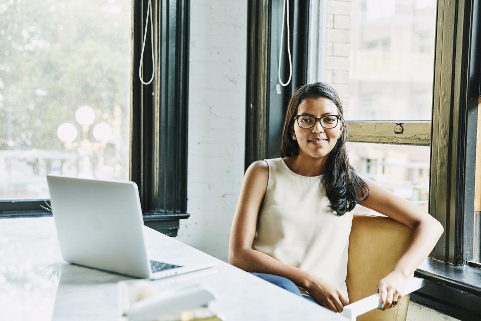 hispanic heritage month, image of a young hispanic woman at a table with a silver laptop in front of her