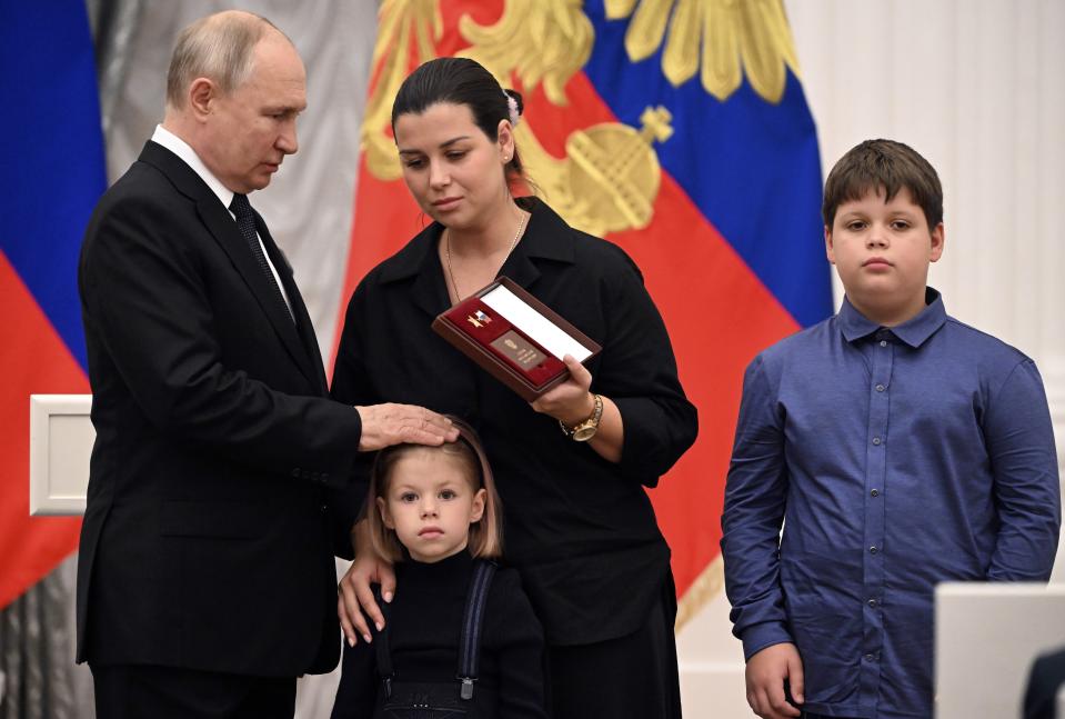 FILE - Russian President Vladimir Putin, left, Angelina Ivanova, the widow of Col. Denis Ivanov, posthumously awarded the title of Hero of the Russian Federation, and her children pose at a ceremony for honoring military personnel who participated in the conflict in Ukraine as well as for prominent Russians for achievements in education, science, medicine, culture, agriculture and industry at the Kremlin's St. Catherine Hall in Moscow, Russia, on Wednesday, Aug. 2, 2023. Putin, who is all but certain to win another six-year term in the March 15-17 presidential election, has sought to consolidate public support by casting the conflict as a fight against the expansionist West that has armed Ukraine in a bid to weaken Russia. (Alexey Maishev, Sputnik, Kremlin Pool Photo via AP, File)