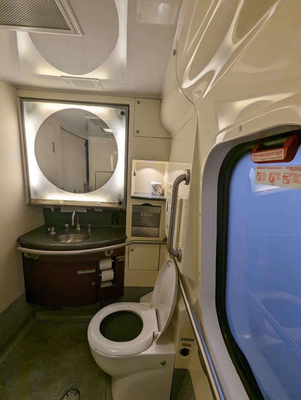 First-class bathroom with lit-up mirror, sink, and toilet