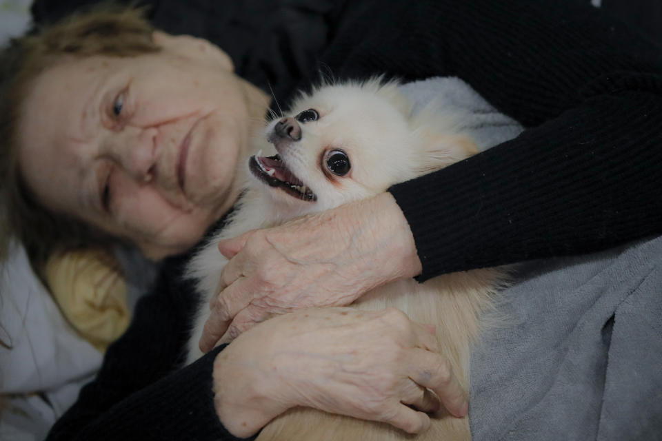 A refugee cradles her dog in a ballroom converted into a refugee shelter.