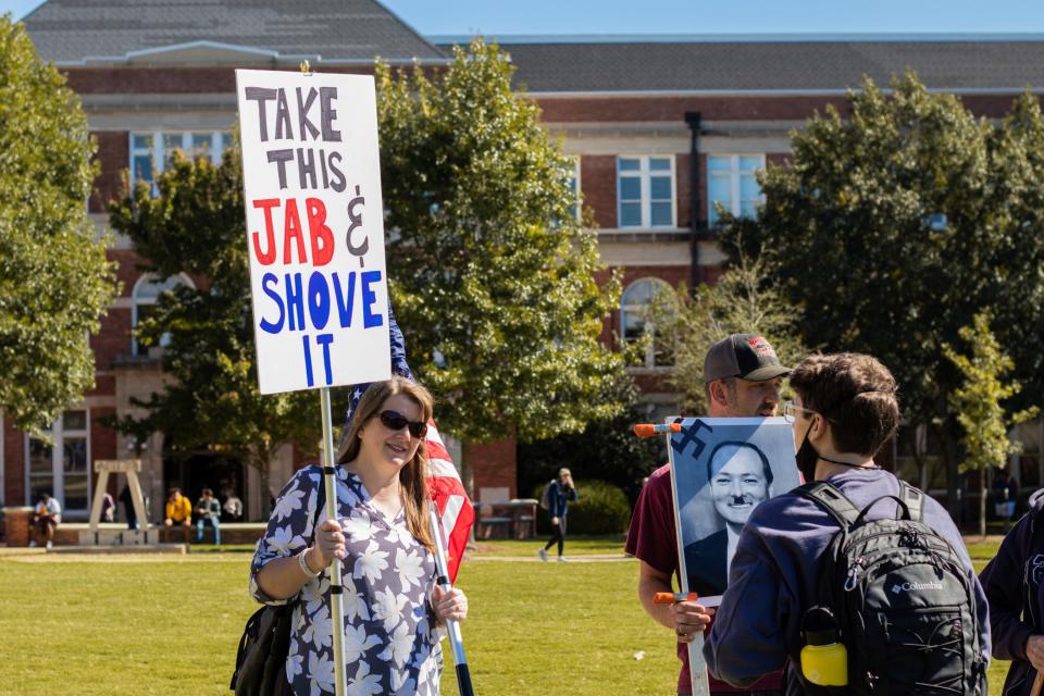 A protester carries a poster displaying a photo of Mississippi State University President Mark Keenum defaced with an Adolf Hitler mustache with a swastika during a demonstration last week against the college's vaccine mandate.
