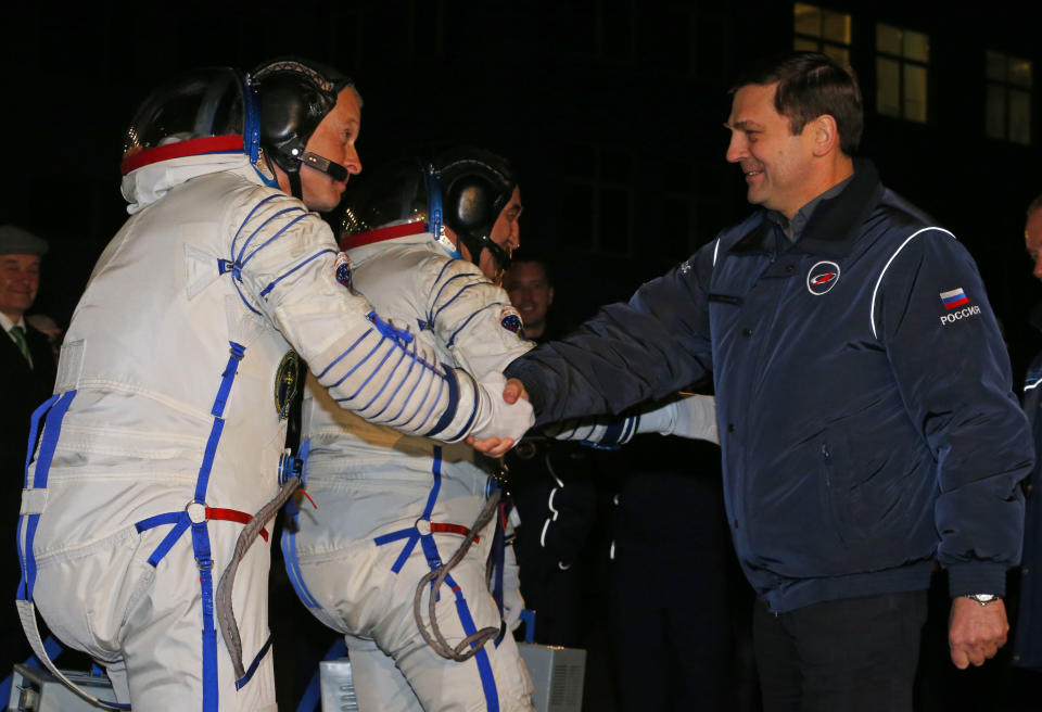 Oleg Ostapenko, right, head of the Russian Federal Space Agency, or Roscosmos, shakes hands with U.S. astronaut Steven, left, a crew member of the mission to the International Space Station (ISS) prior the launch of a Soyuz-FG rocket at the Russian leased Baikonur cosmodrome, Kazakhstan, Wednesday, March 26, 2014. (AP Photo/Dmitry Lovetsky, Pool)