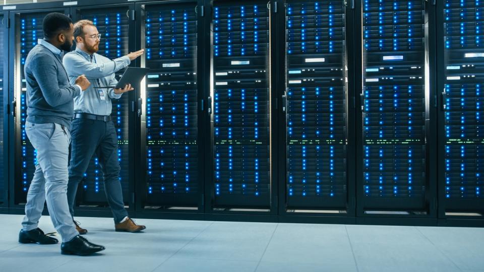 Two people walking inside of a data center checking on servers.