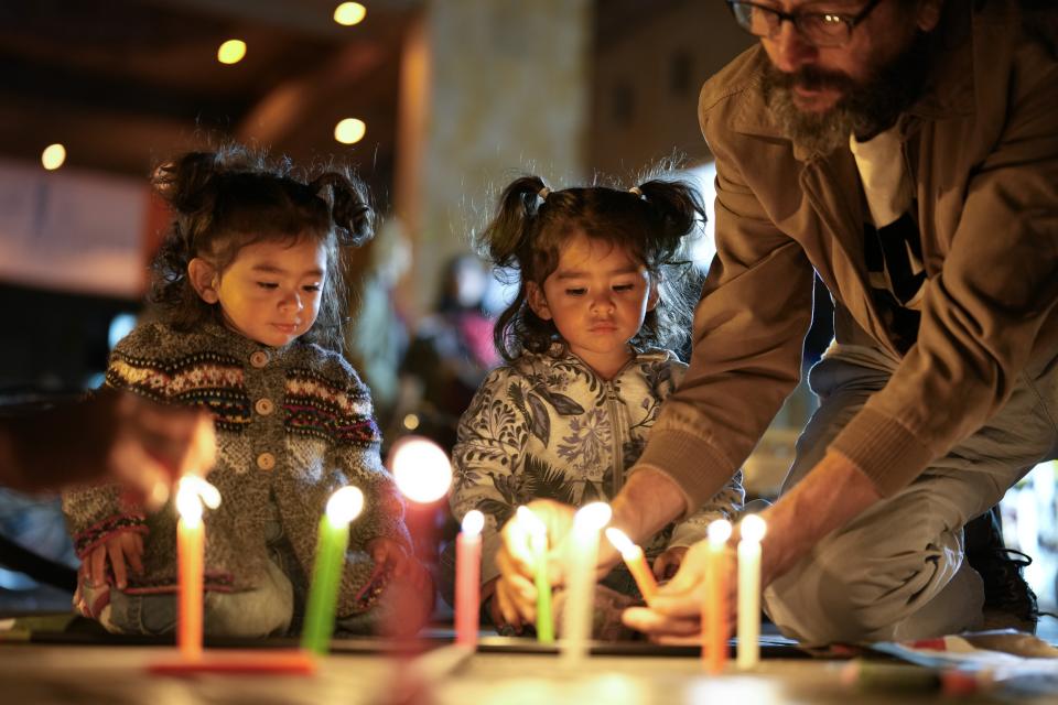A family lights candles during the day of solidarity with the Palestinian people, in Bogota, Colombia, Wednesday, Nov. 29, 2023. (AP Photo/Fernando Vergara)