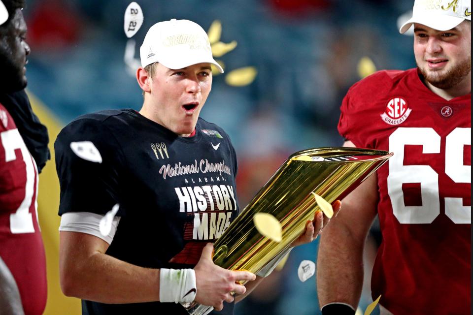 Alabama Crimson Tide quarterback Mac Jones (10) celebrates with the CFP National Championship trophy after beating the Ohio State Buckeyes in the 2021 College Football Playoff National Championship Game.