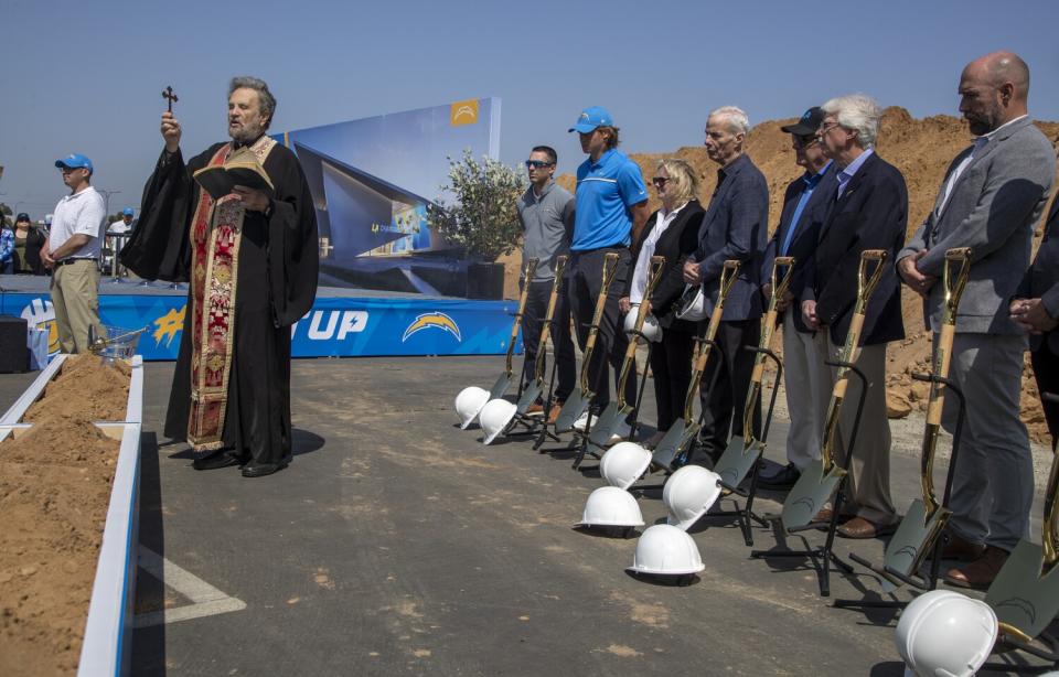 Father John Bakas, left, recites a prayer at a groundbreaking ceremony for a Chargers' headquarters in El Segundo.