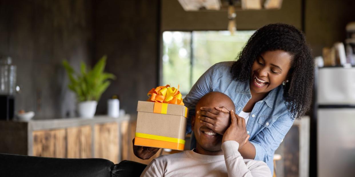 woman at home surprising her husband with a gift