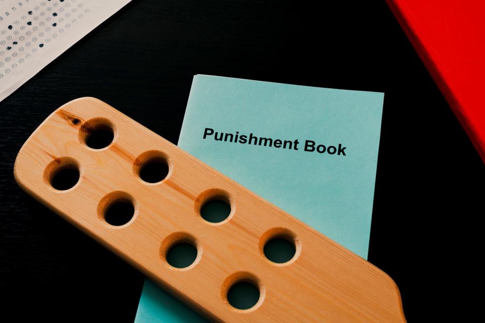 Corporal punishment in school concept. Teacher's desk with spanking device and punishment book.