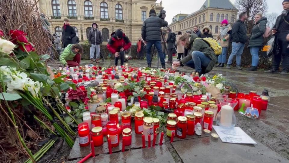 Mourners lay tributes at Prague university after at least 14 killed in mass shooting (PA)