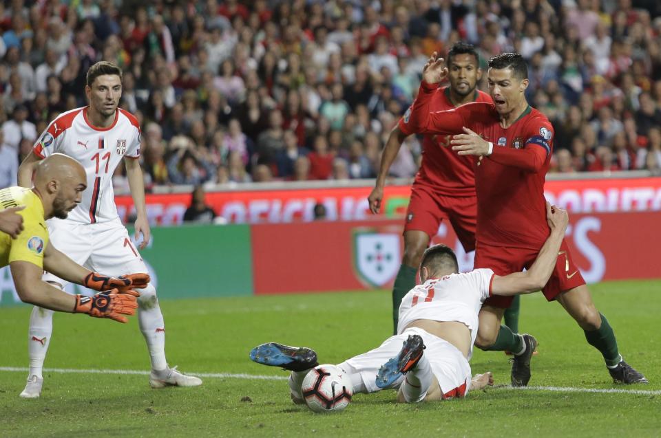 Serbia's Nikola Milenkovic, bottom, and Portugal's Cristiano Ronaldo challenge for the ball during the Euro 2020 group B qualifying soccer match between Portugal and Serbia at the Luz stadium in Lisbon, Portugal, Monday, March 25, 2019. (AP Photo/Armando Franca)