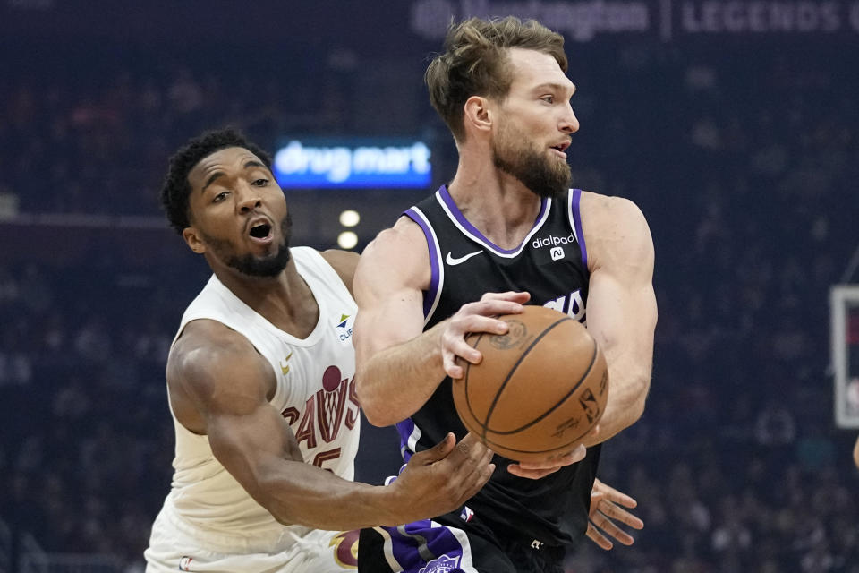 Sacramento Kings forward Domantas Sabonis, right, drives past Cleveland Cavaliers guard Donovan Mitchell, left, in the first half of an NBA basketball game, Monday, Feb. 5, 2024, in Cleveland. (AP Photo/Sue Ogrocki)