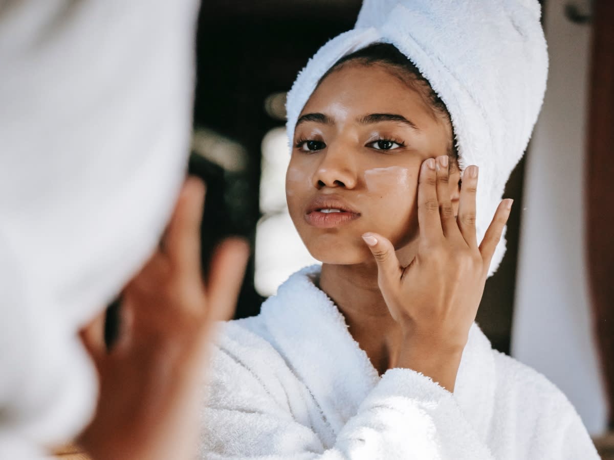 woman putting on skincare in the mirror