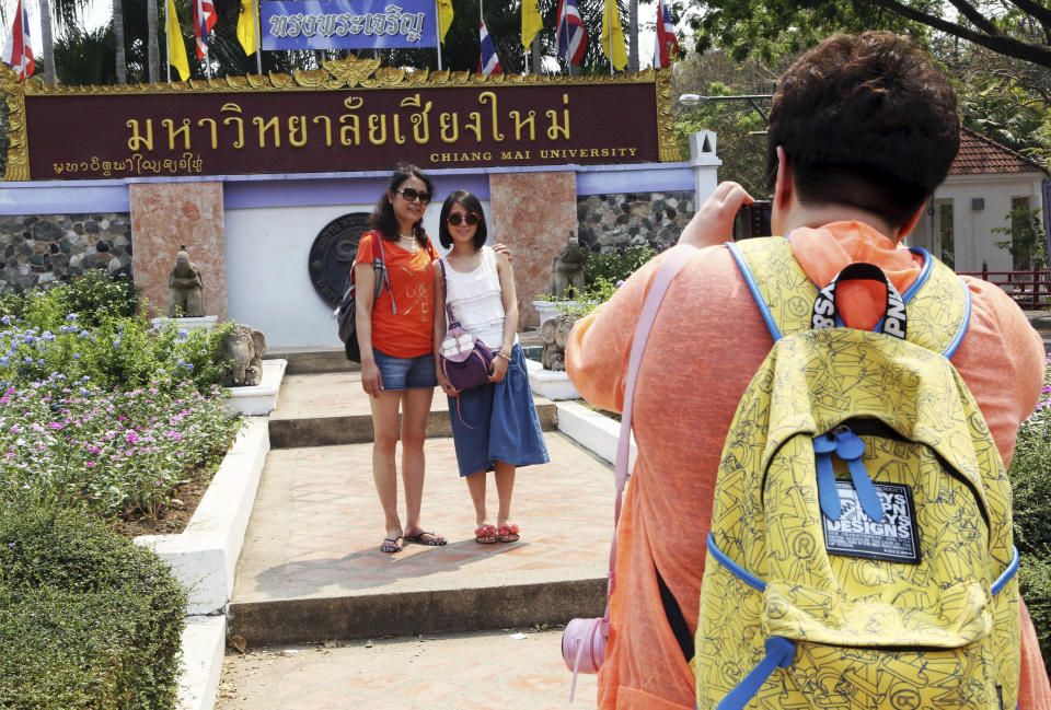 In this March 30, 2014 photo, Chinese tourists pose for a photograph at the main entrance to Chiang Mai University in Chiang Mai province, northern Thailand. The bucolic, once laid-back campus of one of Thailand’s top universities is under a security clampdown. Not against a terrorist threat, but against Chinese tourists. Thousands have clambered aboard student buses at the university, made a mess in cafeterias and sneaked into classes to attend lectures. Someone even pitched a tent by a picturesque lake. The reason: “Lost in Thailand,” 2012 slapstick comedy partly shot on campus that is China’s highest-grossing homegrown movie ever. (AP Photo/Apichart Weerawong)