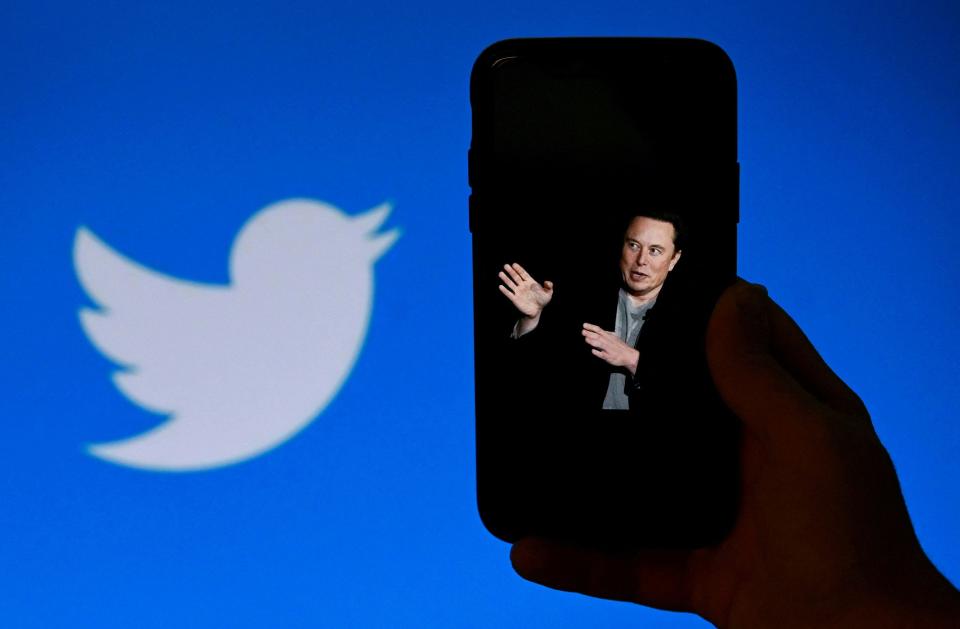 A phone screen displays a photo of Twitter owner Elon Musk with the Twitter logo shown in the background.