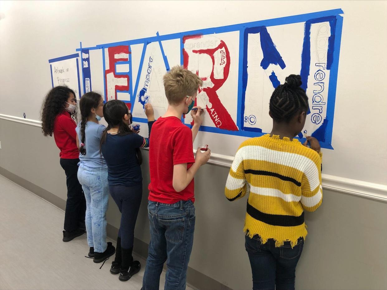 Sixth grader Blake Thompson (center) paints the mural along with other art club members.