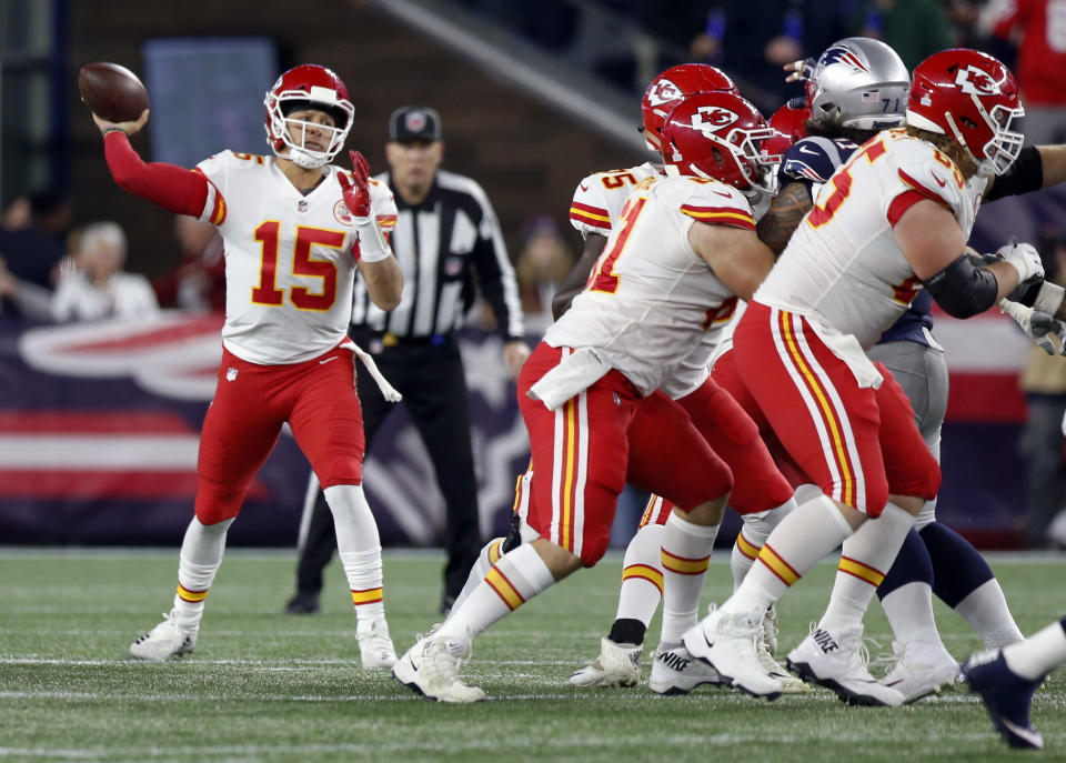 Kansas City Chiefs quarterback Patrick Mahomes, left, passes behind blocking linemen during the first half of an NFL football game against the New England Patriots, Sunday, Oct. 14, 2018, in Foxborough, Mass. (AP Photo/Michael Dwyer)