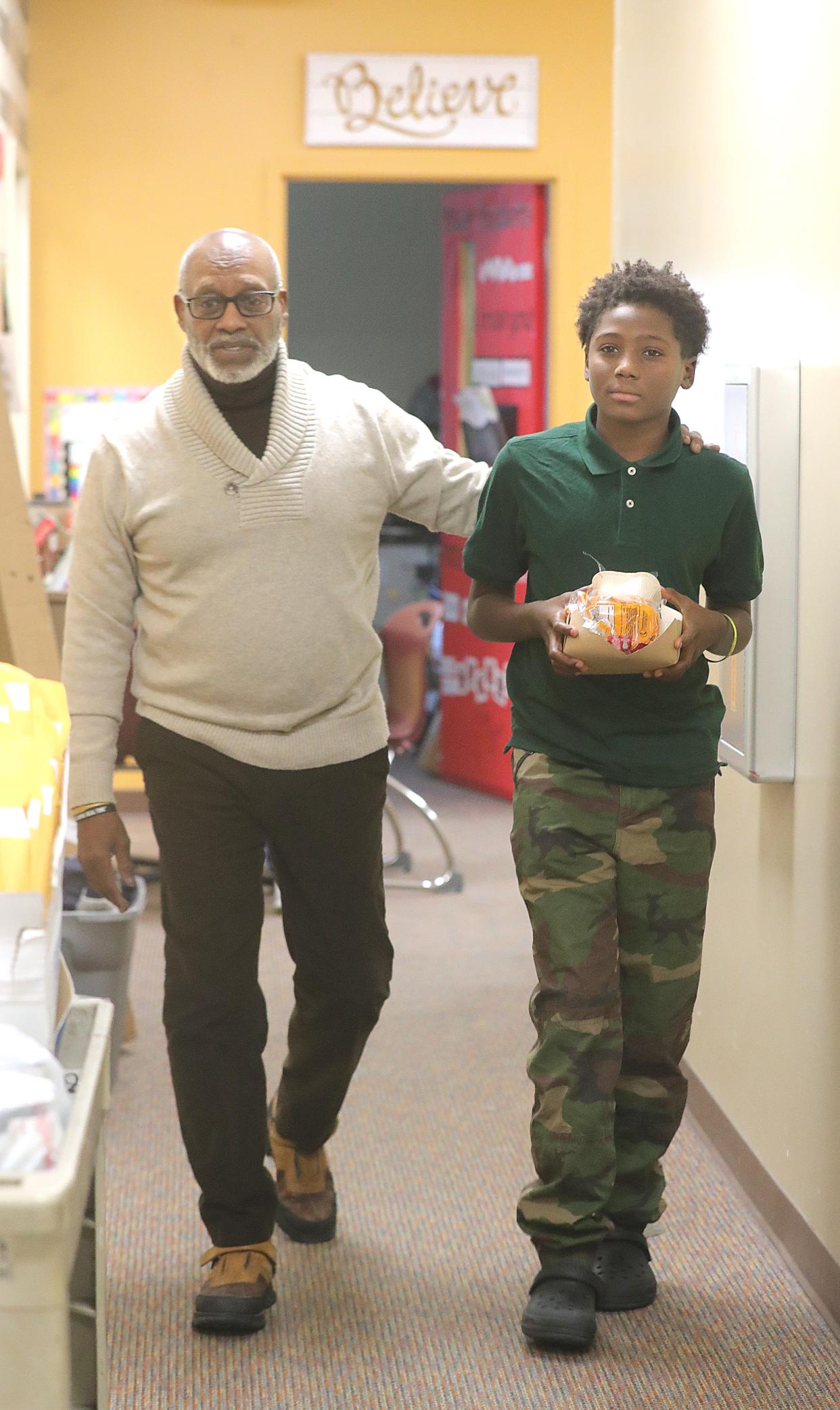 Michael Irby, a mentor with 100 Black Men of Akron Inc., walks with student Dexter Turker to a small group meeting Friday at Crouse Elementary School in Akron.