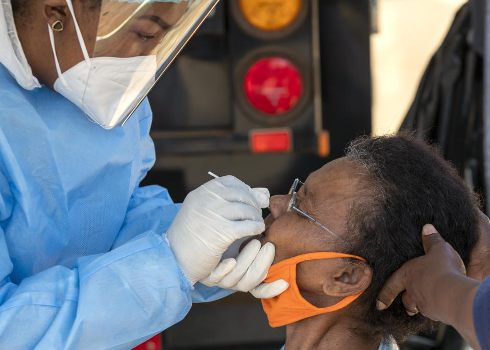 An woman reacts as a heatlh worker collects a sample for coronavirus testing during the screening and testing campaign aimed to combat the spread of COVID-19, in Eldorado Park outside of Johannesburg, South Africa, Monday, Aug. 3, 2020. (AP Photo/Themba Hadebe)