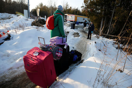 A man talks to a Royal Canadian Mounted Police (RCMP) officer before crossing the US-Canada border into Canada in Champlain, New York, U.S., February 14, 2018. Picture taken February 14, 2018. REUTERS/Chris Wattie