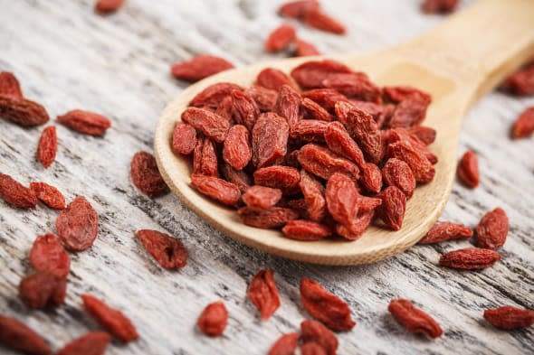 Red dried goji berries in wooden spoon