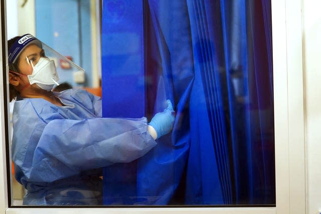 A nurse wearing full PPE adjusts a curtain on a ward for Covid patients at King’s College Hospital