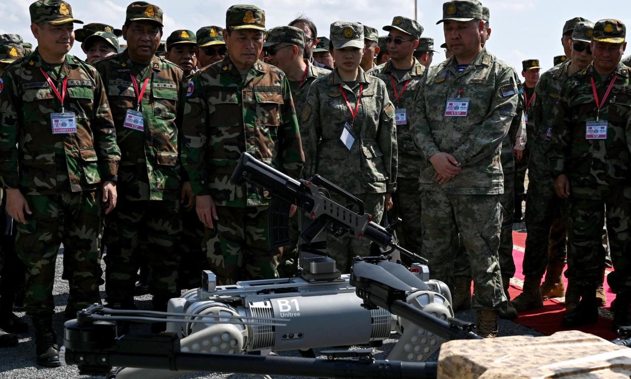 <span>The commander-in-chief of the Royal Cambodia Armed Forces (centre left) at the demonstration by the Chinese army of its machine gun-equipped robot battle dog.</span><span>Photograph: Tang Chhin Sothy/AFP/Getty Images</span>