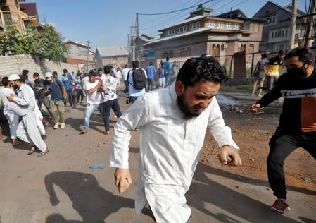 Kashmiris run for cover as Indian security forces fire teargas shells during clashes, after scrapping of the special constitutional status for Kashmir by the Indian government, in Srinagar