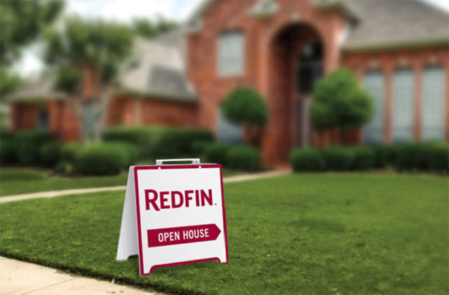 An "open house" sign with a Redfin logo on the lawn of a home for sale.