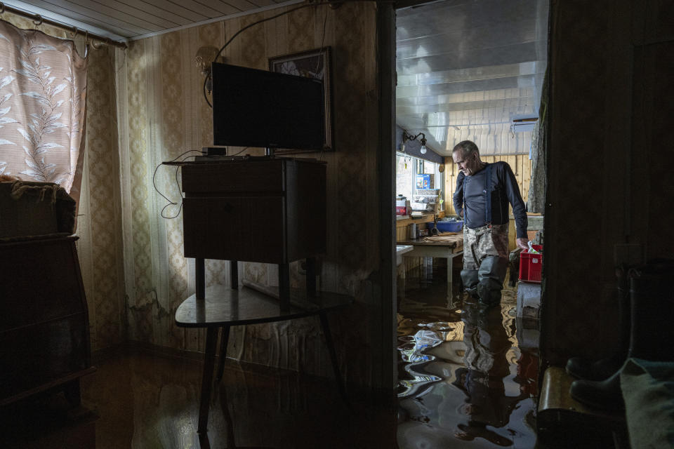 Ihor Medyunov, a local hunter, stands at the kitchen of his flooded house in the island of Kakhovka reservoir on Dnipro river near Lysohirka, Ukraine, Thursday, May 18, 2023.Damage that has gone unrepaired for months at a Russian-occupied dam is causing dangerously high water levels along a reservoir in southern Ukraine. (AP Photo/Evgeniy Maloletka)