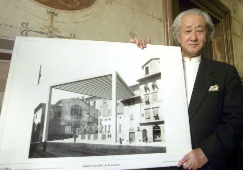 Arata Isozaki, wearing a formal black jacket, holds a rendering for a proposed addition to Florence's Uffizi Museum