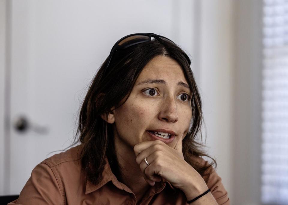 A woman holds her chin in her hand as she speaks.