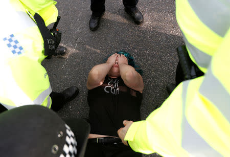 A climate change activist lies on the ground as she is detained by police officers at Waterloo Bridge during the Extinction Rebellion protest in London, Britain April 18, 2019. REUTERS/Peter Nicholls