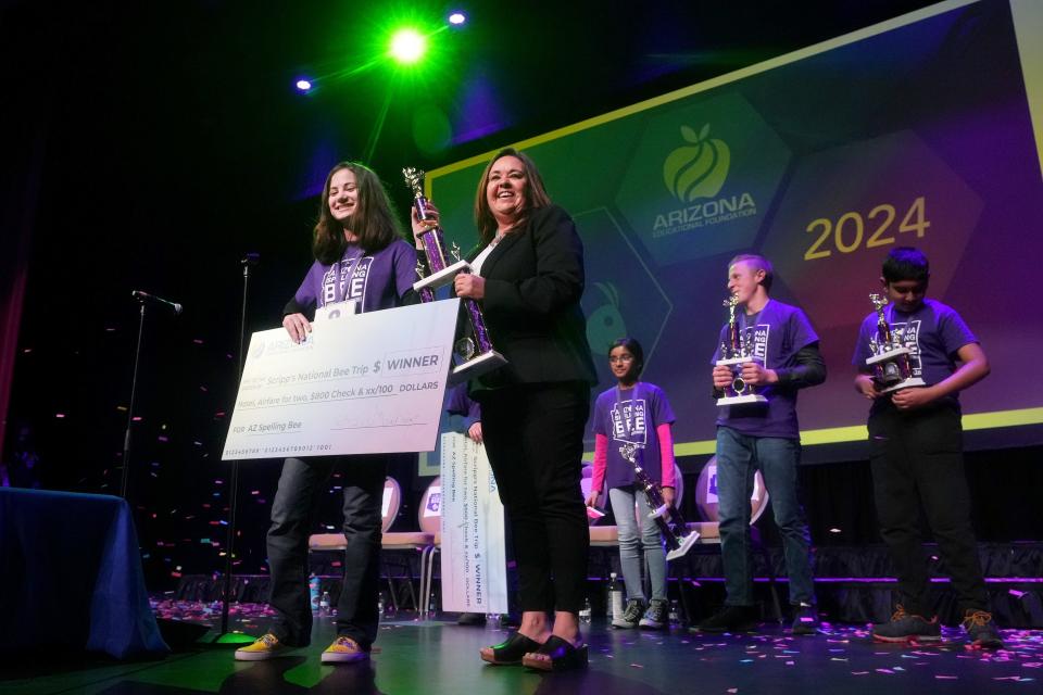 Arizona Spelling Bee champion Aliyah Alpert, 13, is handed her trophy and check by Teresa Hill, deputy director of the Arizona Educational Foundation at the Madison Center in Phoenix for the Arts on March 16, 2024.