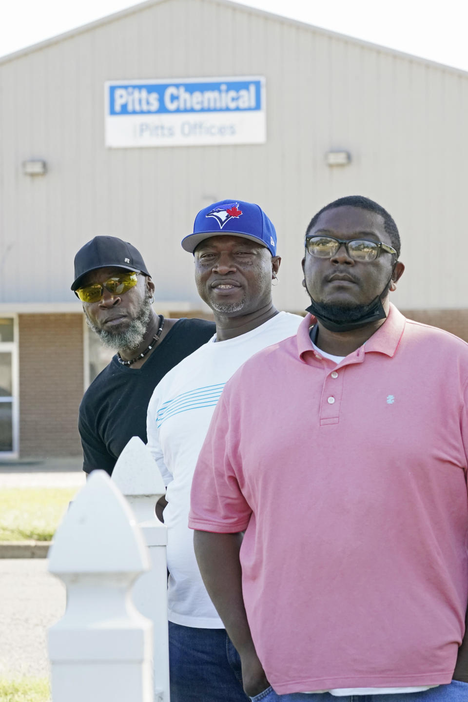 Richard Strong, 50, left, his brother Gregory Strong, 48, center and Stacy Griffin, 42, right, stand across the road from Pitts Chemical offices in Indianola, Miss., Thursday, Sept. 9, 2021. The three are among six Black farmworkers in Mississippi who say in a new lawsuit that their former employer, Pitts Farm Partnership, has brought white laborers from South Africa to do the same jobs they were doing, and that the farm has been violating federal law by paying the white immigrants significantly more for the same type of work. (AP Photo/Rogelio V. Solis)