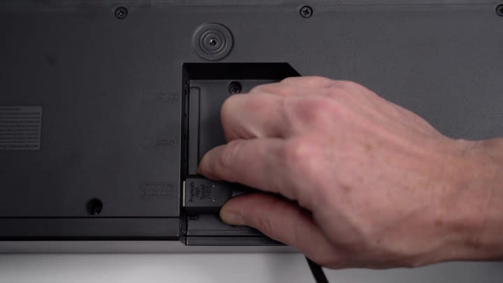 A man's hand inserting a cable into the HDMI ARC port on the back of a TV. 