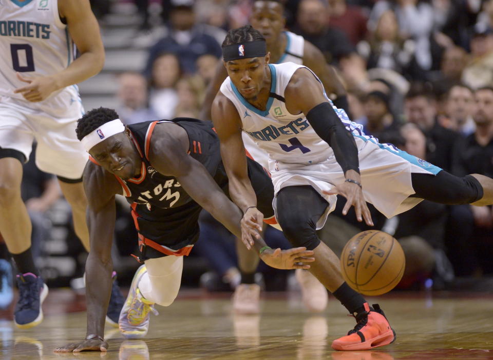 Toronto Raptors forward Pascal Siakam (43) and Charlotte Hornets guard Devonte' Graham (4) vie for control of the ball during second-half NBA basketball game action in Toronto, Friday, Feb. 28, 2020. (Nathan Denette/The Canadian Press via AP)