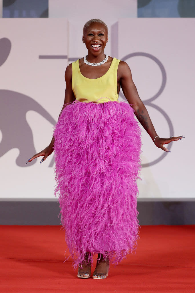 Cynthia Erivo in a feathered magenta and bright yellow calf-length dress for the red carpet of "Last Night In Soho"