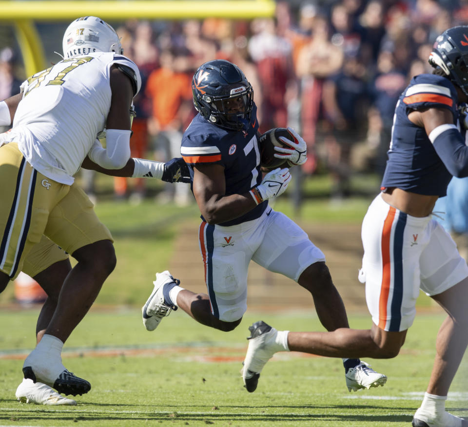 Virginia running back Mike Hollins (7) runs for a gain as he is pursued by Georgia Tech defensive lineman Eddie Kelly (97) during the first half of an NCAA college football game Saturday, Nov. 4, 2023, in Charlottesville, Va. (AP Photo/Mike Caudill)