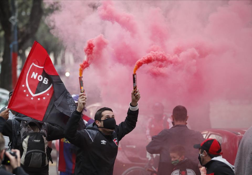 A man wearing a protective face mask holds flares during a caravan organized by the soccer club fans of Newell's Old Boys in the hometown of Leonel Messi, in Rosario, Argentina, Thursday, Aug. 27, 2020. Fans hope to lure him home following his announcement that he wants to leave Barcelona F.C. after nearly two decades with the Spanish club. (AP Photo/Natacha Pisarenko)