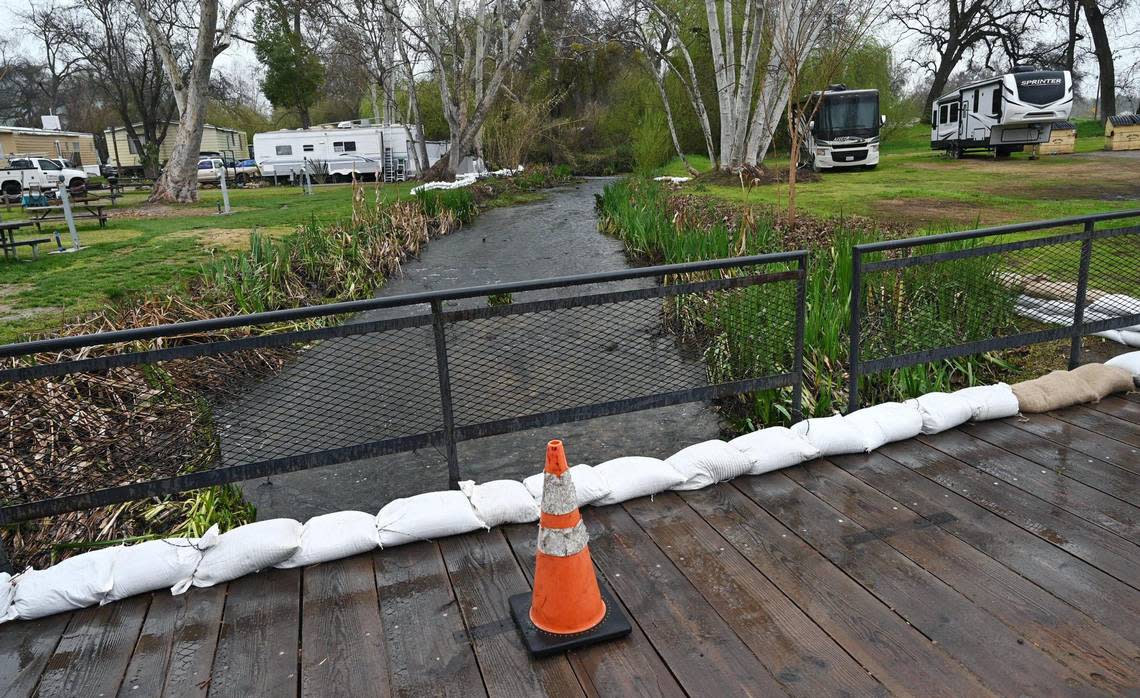 Sandbags are placed along a bridge and along property, background, where a small creek flows through Riverbend RV Park Thursday, March 9, 2023 east of Fresno.