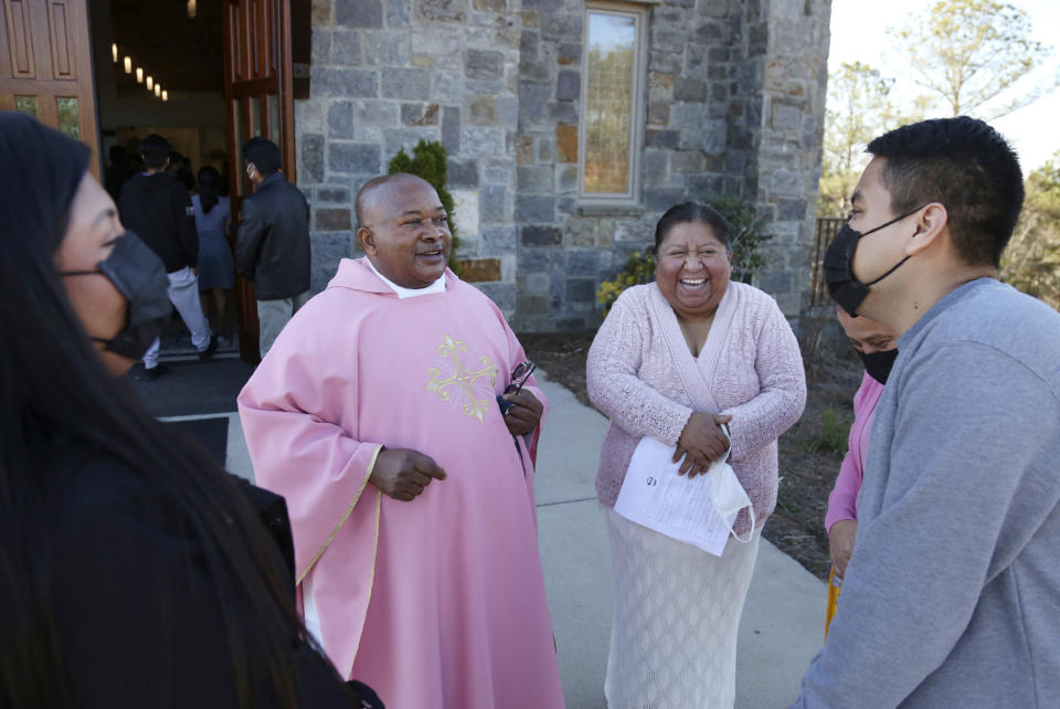 The Rev. Athanasius Abanulo talks with Giselle Perez, left, Elvira Allende, center right, and Efren Perez, right, after Mass on Sunday, Dec. 12, 2021, at Immaculate Conception Catholic Church in Wedowee, Ala. Originally from Nigeria, Abanulo is one of numerous international clergy helping ease a U.S. priest shortage by serving in Catholic dioceses across the country. (AP Photo/Jessie Wardarski)